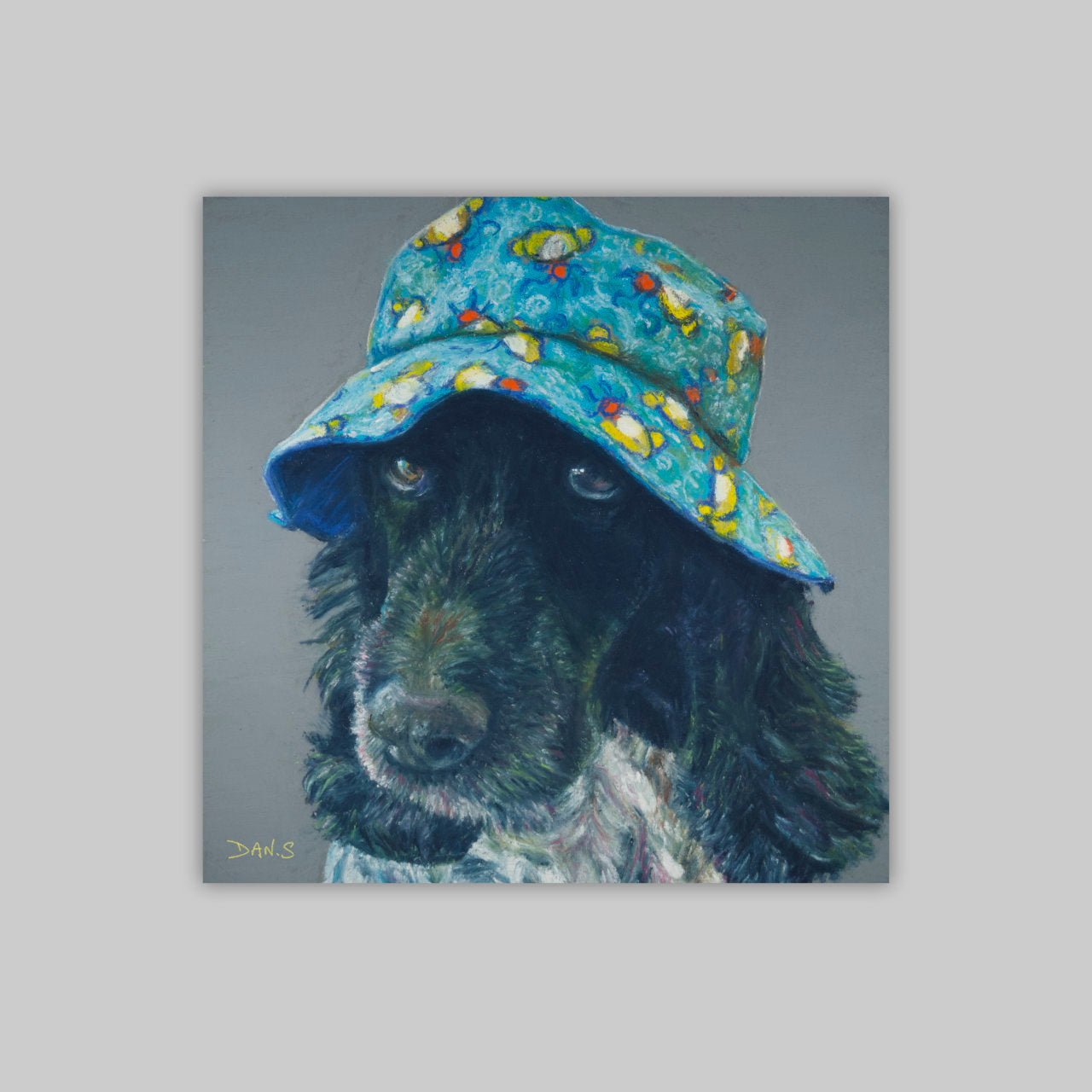 Picture of a cocker spaniel wearing a colourful bucket hat on a grey background