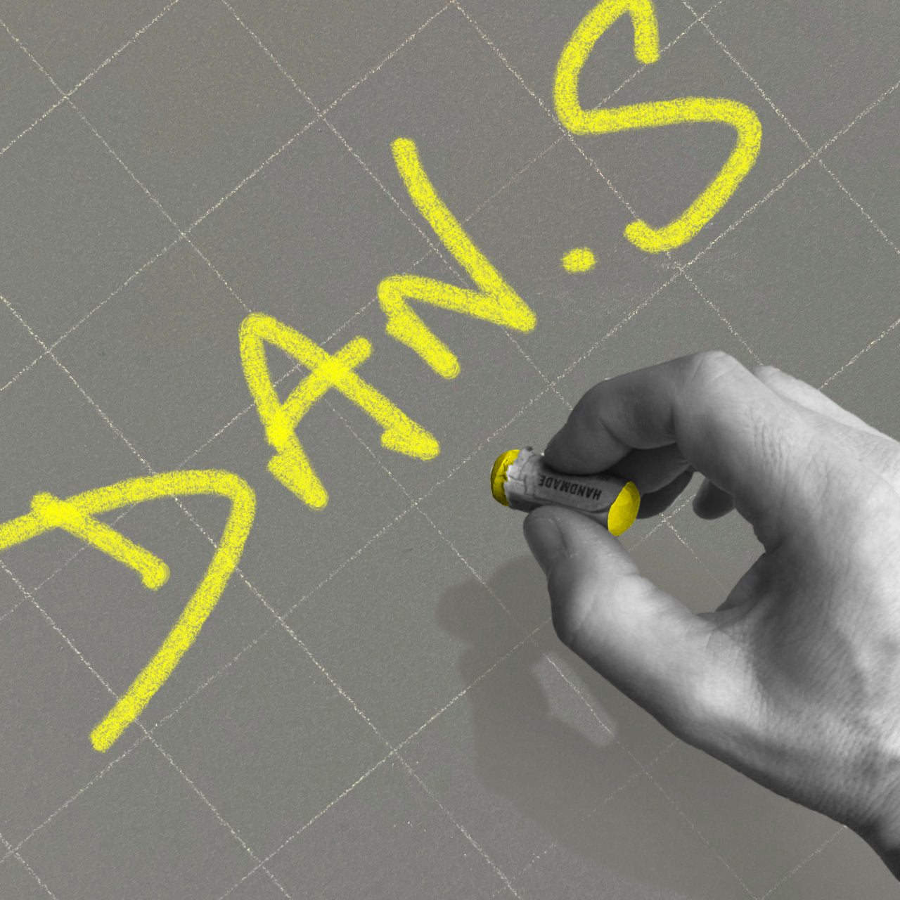 Hand holding a yellow marker writing 'DAN'S' on a gray grid background