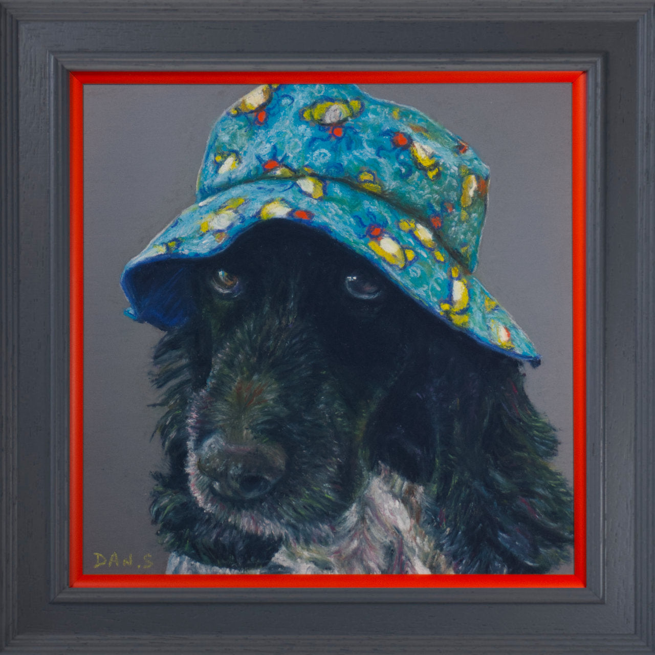 Picture of a cocker spaniel wearing a colourful bucket hat on a grey background in a grey frame with orange border
